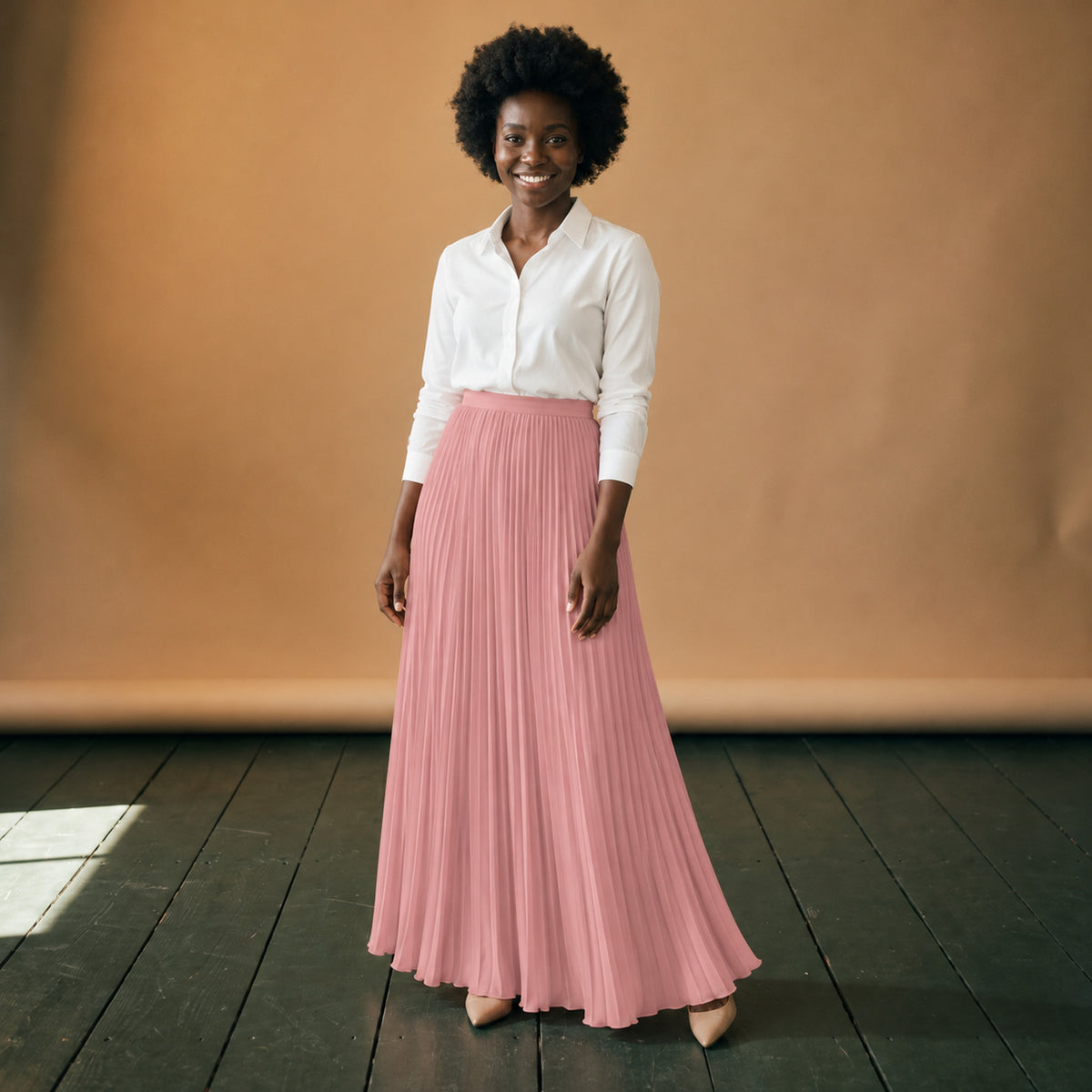 Jupe longue années 80 plissée rose taille haute portée en studio avec un chemisier blanc, vue de face Imagen