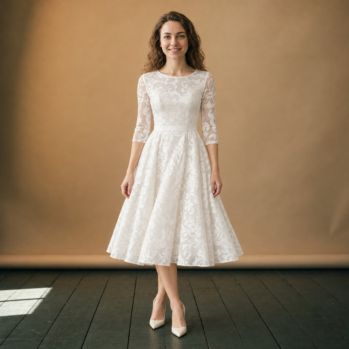 Robe de mariée mi-longue vintage en coton et dentelle portée en studio, manches trois-quarts, vue de face Imagen
