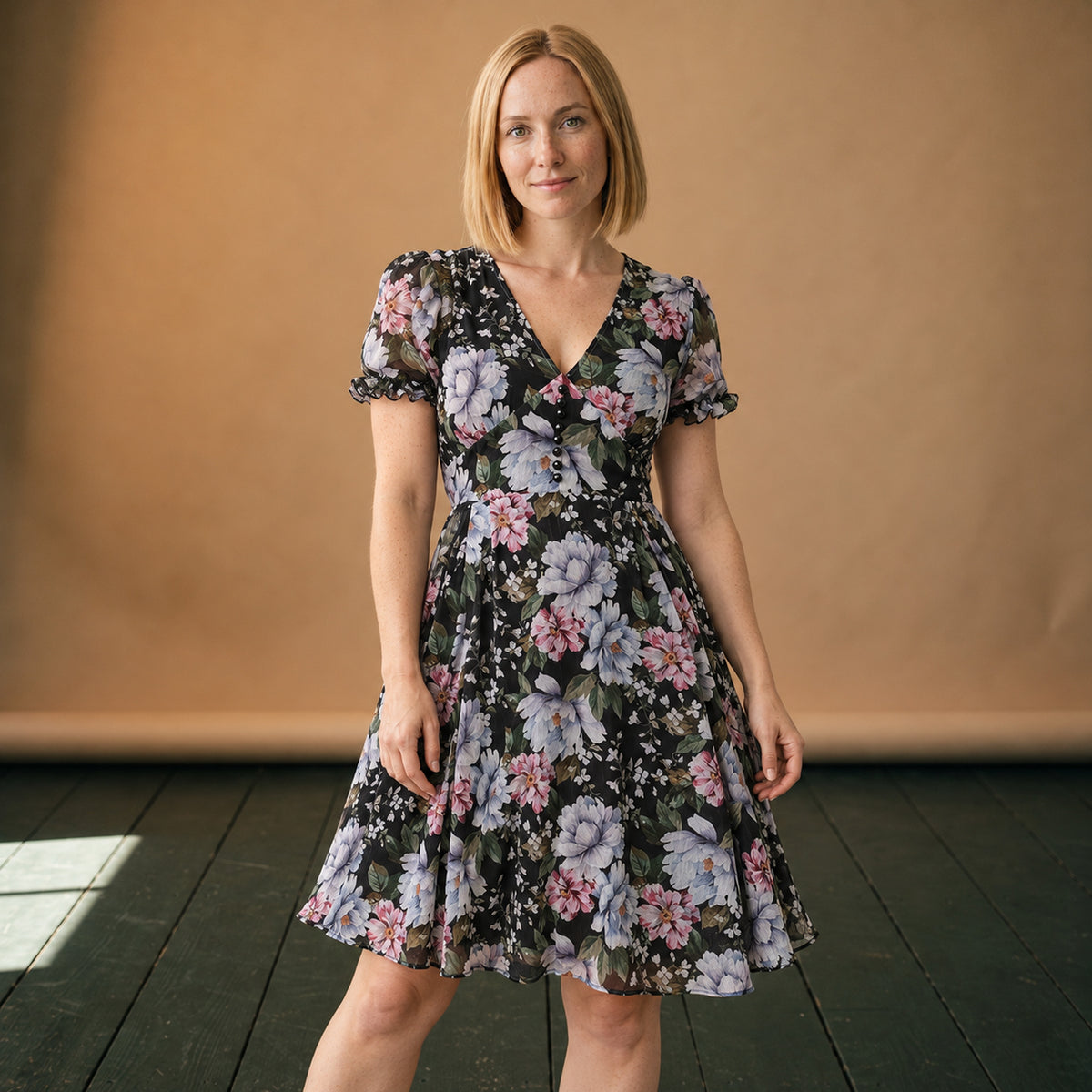 Robe vintage années 50 fleurie noire portée en studio, col V et jupe évasée, vue de face Imagen