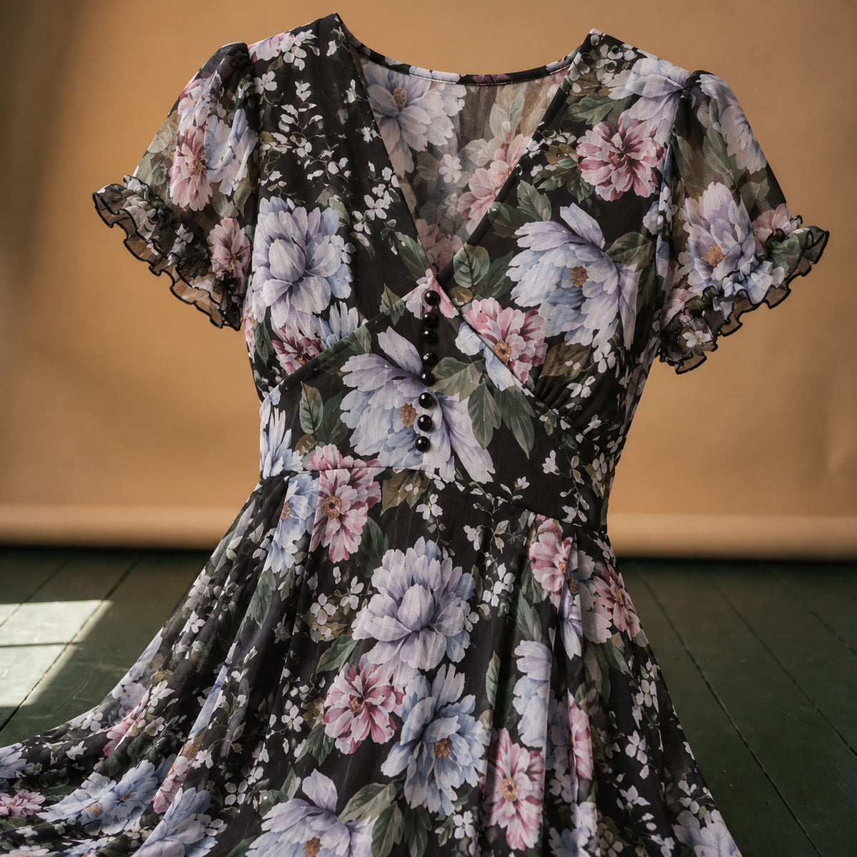 Gros plan sur l'imprimé fleuri et les boutons du corsage de la robe vintage années 50 noire Imagen